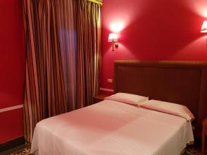 a bedroom with a white bed with red walls at Hotel Kennedy in Rome