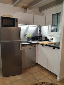 uma cozinha com um frigorífico de aço inoxidável e armários brancos em Voile et Plage, Villa 3 étoiles à La Trinité sur Mer em La Trinité-sur-Mer