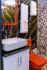 W łazience znajduje się czerwona toaleta i umywalka. w obiekcie Hôtel La Principauté Douala Bonapriso w mieście Duala