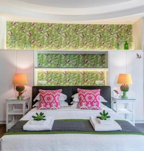 una camera da letto con un grande letto con cuscini rosa di Kouloura Liston Suite a Città di Corfù