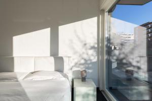1 dormitorio con cama blanca junto a una ventana en Roggia Apartments by Quokka 360 - central flats with parking space, en Lugano
