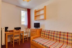 Habitación con sofá y mesa con escritorio. en Vacancéole - Résidence Côte Brune, en Les Deux Alpes