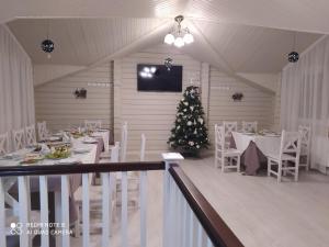 ein Esszimmer mit Weihnachtsbaum und weißen Tischen und Stühlen in der Unterkunft Pogar White in Slawske