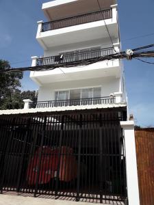 ein weißes Haus mit einem Tor davor in der Unterkunft Khun Pich Apartments in Siem Reap