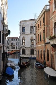 een groep gondels in een kanaal tussen twee gebouwen bij Casa Dei Pittori Venice Apartments in Venetië