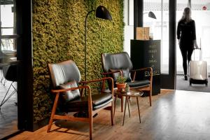 2 Stühle und ein Tisch vor einer grünen Wand in der Unterkunft Hotel Hogerhuys - adults only in Noordwijk aan Zee