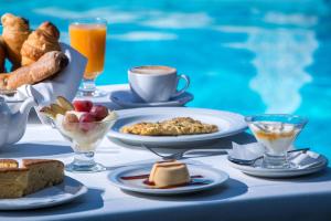 a table with breakfast foods and drinks next to a swimming pool at Zeus Throne Suites in Afionas
