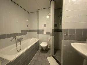 uma casa de banho com uma banheira, um WC e um lavatório. em Hotel DoniaState em Oost-Vlieland