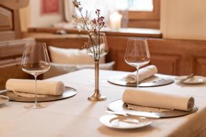 einen Tisch mit zwei Weingläsern und einem weißen Tischtuch in der Unterkunft Unterwirt - Das kleine Gourmethotel in Ebbs