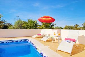 a patio with a pool and a red umbrella at Villa Margarita in Carvoeiro