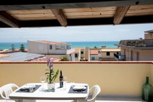 d'une table et de chaises sur un balcon avec vue sur l'océan. dans l'établissement DELPOSTO Marina di Ragusa SR, à Marina di Ragusa