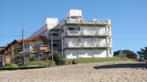 un edificio blanco en la playa junto a una playa en Departamento Villa Gesell Centro Sobre Playa y 114 Vista al Mar en Villa Gesell