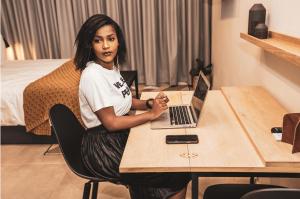 uma mulher sentada numa mesa com um laptop em Blackbrick Sandton One em Joanesburgo