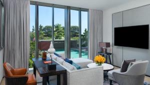 a living room with a couch and chairs and a tv at Hyatt Regency Phnom Penh in Phnom Penh
