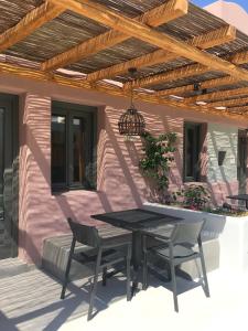 a patio with a table and chairs under a wooden pergola at Terra Nera Suites in Perivolos