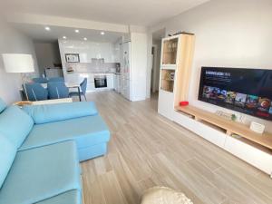 een woonkamer met een blauwe bank en een flatscreen-tv bij A beautiful apartment with a beach view - La Tejita - El Medano in El Médano