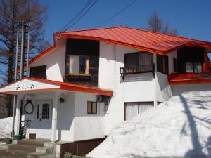 a white house with a red roof in the snow at Alpha Live Madarao in Madarao Kogen