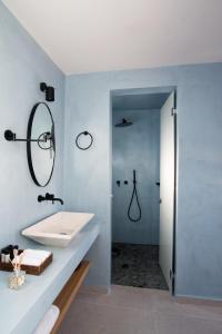 a white bathroom with a sink and a shower at Terra Nera Suites in Perivolos
