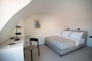 a bedroom with a white bed and a chair at Terra Nera Suites in Perivolos