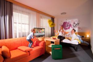 eine Familie, die ein Videospiel im Wohnzimmer spielt in der Unterkunft Hotel Orel in Maribor