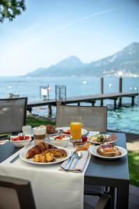 einen Tisch mit Teller mit Lebensmitteln darüber in der Unterkunft Hotel Du Lac - Relax Attitude Hotel in Brenzone sul Garda