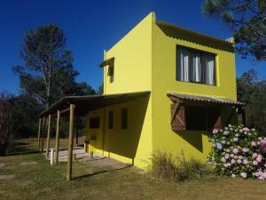 a yellow house with flowers in front of it at Riyadh - en el bosque a metros de la playa in Rincón de los Oliveras