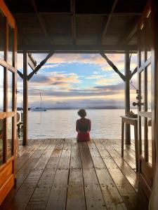 a woman sitting on a dock looking out at the water at Casa Acuario Boutique Hotel in Bocas del Toro