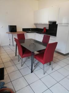a kitchen with a table and four red chairs at logement entier au calme in Villers-Outréaux