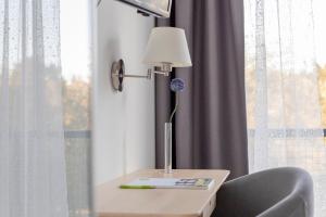 a table with a lamp and a chair next to a window at Bildungs- und Tagungshaus Haus Neuland in Bielefeld