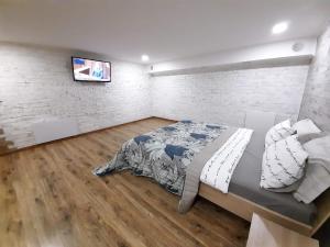 a bedroom with a bed and a tv on a brick wall at Charlotte -двухуровневая Студия в Центре in Kremenchuk