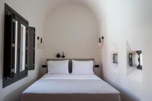 a bedroom with a white bed and two windows at Terra Nera Suites in Perivolos