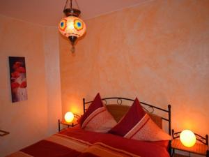 a bedroom with a bed with red sheets and a chandelier at Ferienwohnung Omert in Ehrenberg