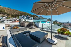 a patio with a couch and an umbrella at The Solis Penthouse in Cape Town