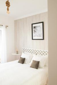 a white bedroom with a large bed with white pillows at Casa do Ar in Sesimbra