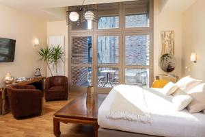 a bedroom with a white bed and a large window at Logis Hôtel Restaurant Auberge de la Tour in Marcolès