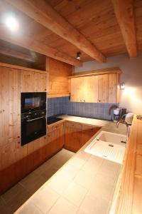 a kitchen with wooden cabinets and a black appliance at Vacancéole - Résidence l'Alba in Les Deux Alpes