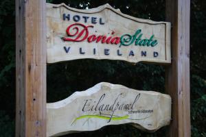 a wooden sign with a sign for a restaurant at Hotel DoniaState in Oost-Vlieland