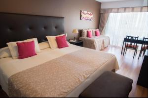 una camera da letto con un grande letto con cuscini rossi e rosa di Gran Hotel Continental a Mar del Plata