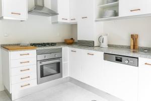 a kitchen with white cabinets and a stove at Casa do Ar in Sesimbra