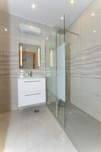 La salle de bains est pourvue d'une douche en verre et d'un lavabo. dans l'établissement High In The Sky, à Portimão