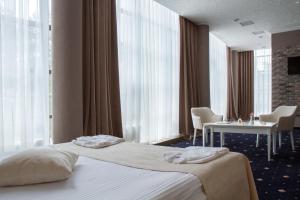 a hotel room with a bed and a table and windows at City Holiday Resort & SPA in Kyiv