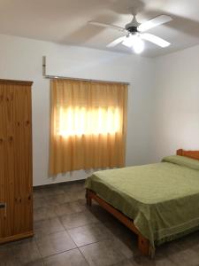 1 dormitorio con 1 cama y ventilador de techo en Do Sol. Departamentos de Mar en Las Toninas