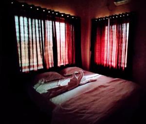 a room with a bed with two windows and a towel on it at White smoke villa in Igatpuri