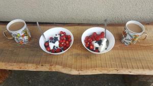 quatre tasses de café et trois bols de fruits sur une table en bois dans l'établissement Borywood, à Małe Gacno