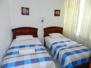 two beds in a small room withacers at Departamento Marifer in Tacna