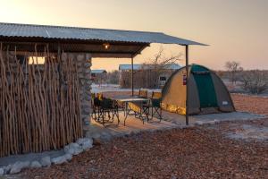 a tent and a table and chairs in a field at Etosha Trading Post Campsite in Okaukuejo