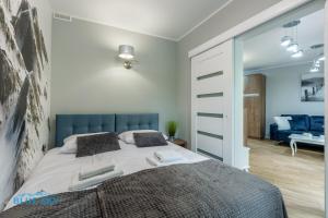 a bedroom with a large bed and a living room at Apartamenty BlueSky - Nad Łomnicą 2B - blisko centrum i sklepów in Karpacz