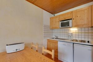 kuchnia ze stołem i kuchenką mikrofalową w obiekcie Vacancéole - Résidence Lauvitel w mieście Les Deux Alpes