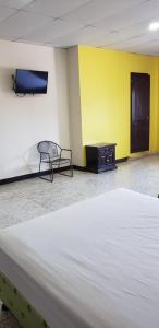 a bedroom with a large white bed and a chair at Hotel El Dorado in La Ceiba