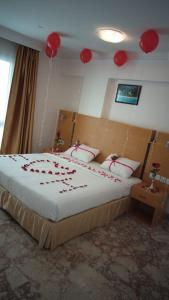 a bedroom with a bed with red decorations on it at Al Reef Hotel in Muscat